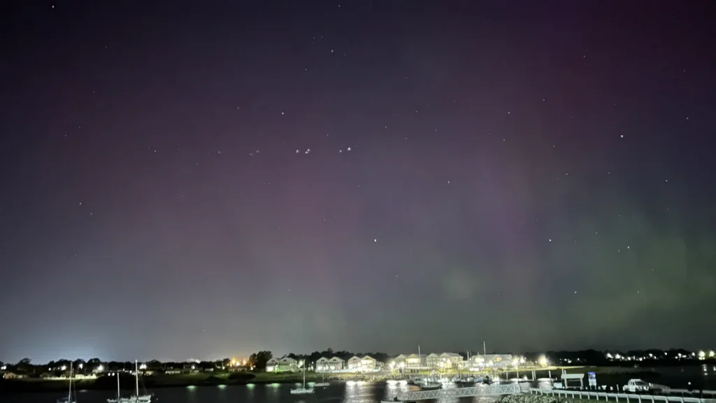 The aurora australis over George Town, Tasmania, seen as a purple and green glow over the town's waterfront at night.